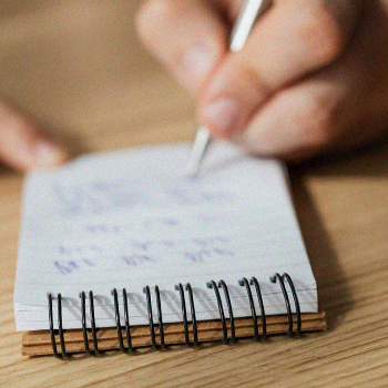 Hand writing something on a notepad