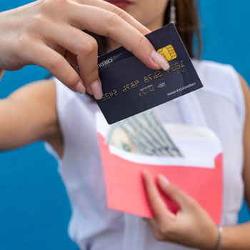 A hand view of a woman showing her credit card while holding cash on the other hand