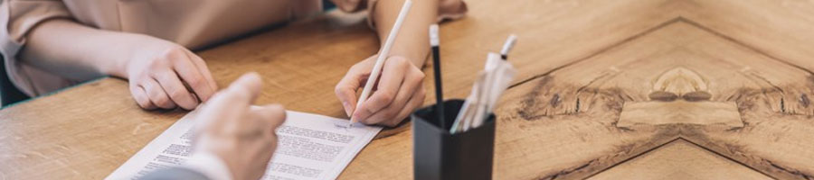 Hand view of a person signing a paper using a ballpen