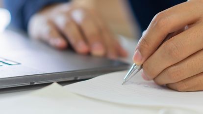 A man writing on a notebook for his GRE verbal prep