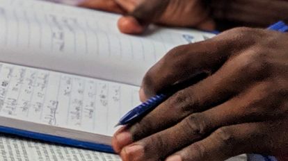 Man holding a pen and reading on a book